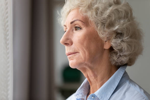 istock Close up thoughtful older woman looking out window at home 1201295562