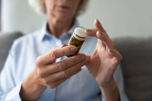 istock Close up older woman holding bottle with pills, reading instruction 1201295564