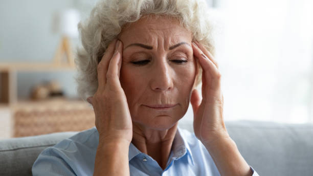 istock Close up unhappy older woman touching temples, suffering from headache 1201295566