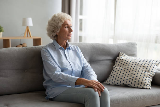 istock Thoughtful older woman sitting on couch, lost in thoughts 1201295567