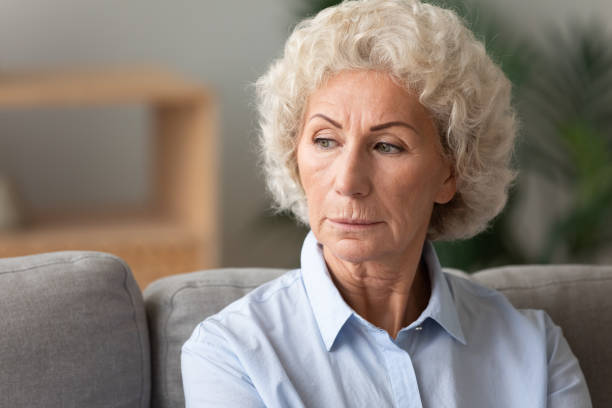 istock Head shot older woman lost in thoughts, sitting on couch 1201295574