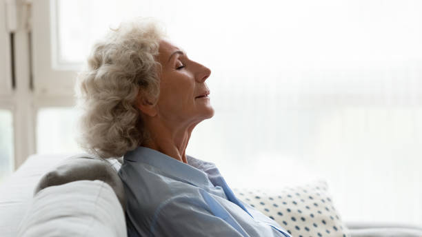istock Head shot profile peaceful older woman relaxing on couch 1201295587