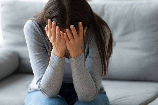 istock Unhappy young woman covering face with hands, crying alone 1201295603