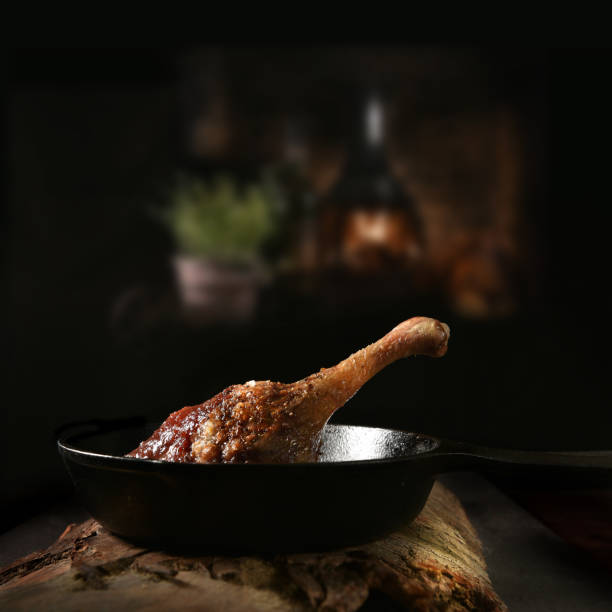 Roasted Duck Leg With Plum Sauce Roasted duck leg with plum sauce shot against a rustic, dark background. Copy space. confit stock pictures, royalty-free photos & images