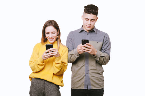 istock Hipster couple smiling, using smartpones standing over white backgound 1201300501