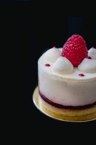 istock Luxury white cheesecake mousse cake decorated with fresh raspberries on a dark background. Flat lay. Close-up. Copy space 1201301582