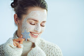 relaxed stylish woman with white facial mask holding snowflake
