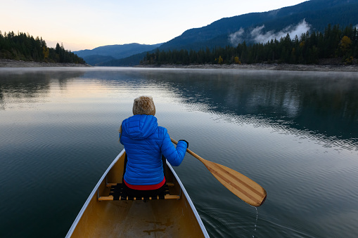 Woman paddling a canoe in BC, Canada. Women adventuring in the great outdoors.
