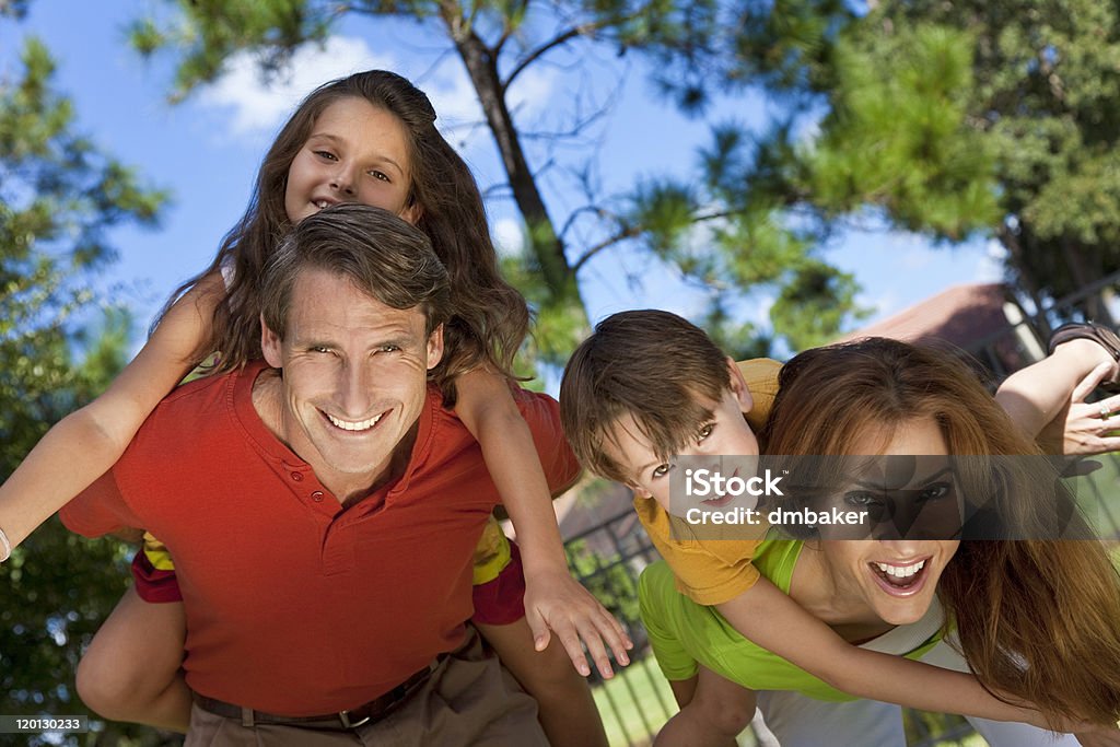 Happy Family Having Fun Outside In Park An attractive happy, smiling family of mother, father, son and daughter having fun outside in a park in warm summer sunshine 30-39 Years Stock Photo