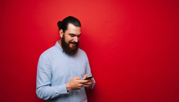 istock Photo of bearde man, holding a mobile and looking at him 1201303868