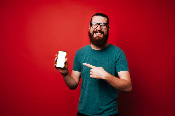 istock Smiling hipster bearded man pointing on his new smarphone 1201305150