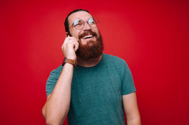 istock Cheerful bearded man talking on phone 1201305191