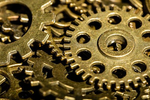 A steampunk macro of a pile of tiny industrial gears and wheels showing dirt and rust from past use. Very sharp focus on a single gear with a medium Depth of Field.