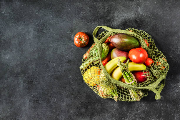 istock Fresh vegetables and fruits in a green string bag on a black background. No plastic, only natural materials and natural products. 1201311112