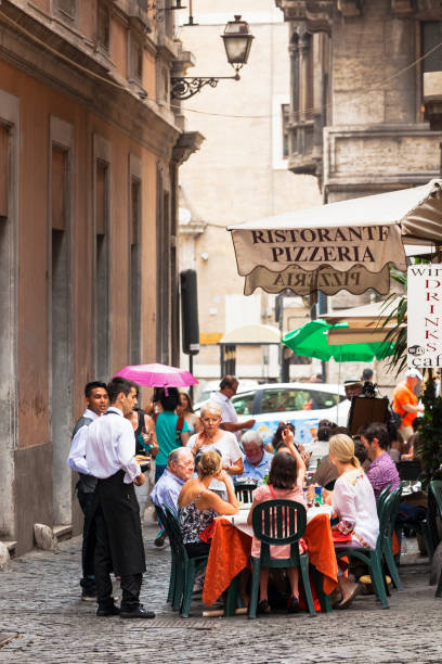 Rome, Italy - June 27, 2015. People at a sidewalk cafe on a narrow street in the city of Rome the capital of Italy.