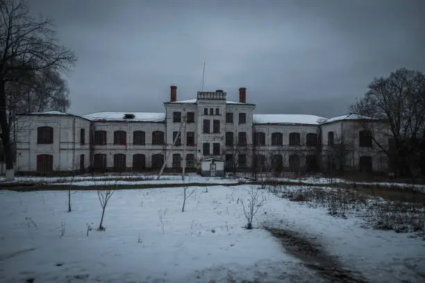 Dark and creepy abandoned haunted mental hospital in winter.