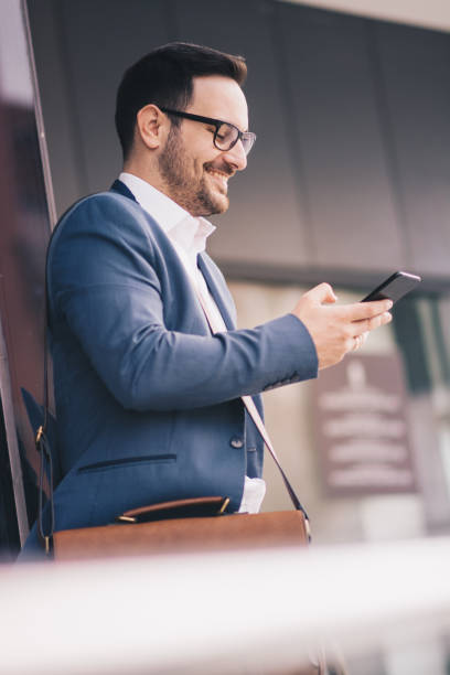 A young man in suit using his phone outdoors.