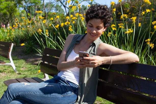 istock young woman cute texting on a park bench 1201324209