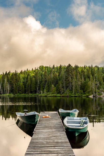 Fishing lake in early morning. A coffee cup with a towel left on a wharf with fishing boats on a lake in a forest of Lanaudiere area in Quebec during the fishing season. city break photos stock pictures, royalty-free photos & images