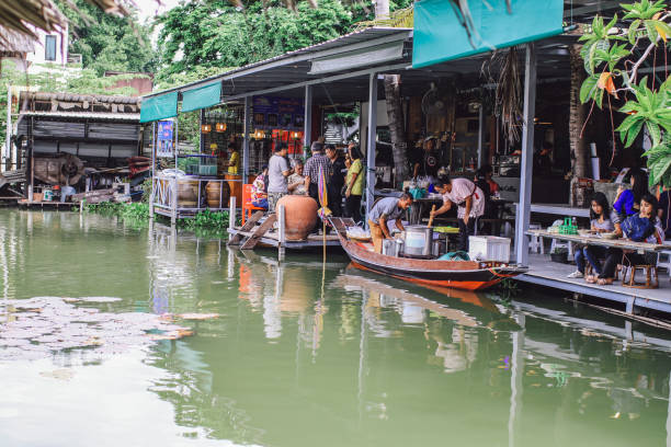 bangkok, thailand - 23. januar 2020 - thailändischer traditionsverkäufer auf dem boot auf dem schwimmenden markt khlong lat mayom in bangkok.he boote sind voll von obst und gemüse, die verkäufer auf dem schwimmenden markt beitreten. es gibt viele touri - stand up paddling stock-fotos und bilder