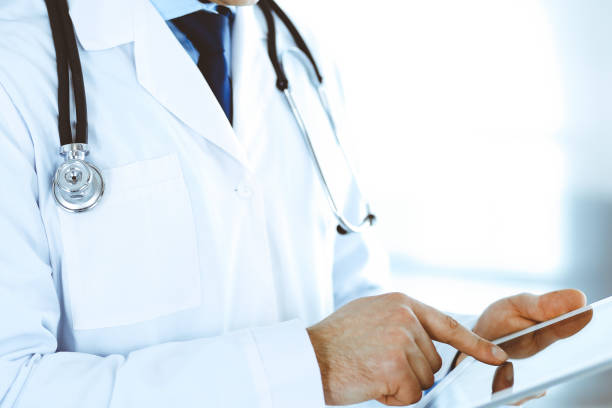 istock Doctor man using tablet computer for network research or virtual disease treatment, hands close-up. Perfect medical service in clinic. Modern medicine, medic data and healthcare concepts. Toned picture 1201328215
