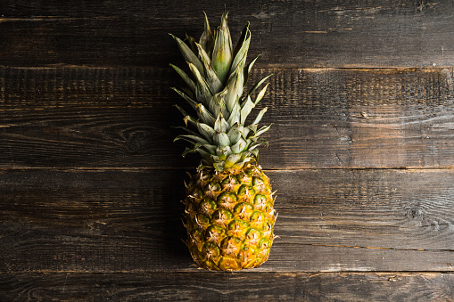 Fresh ripe pineapple on the rustic background. Selective focus.