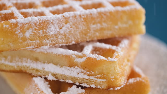 Pouring powdered sugar on to the waffles