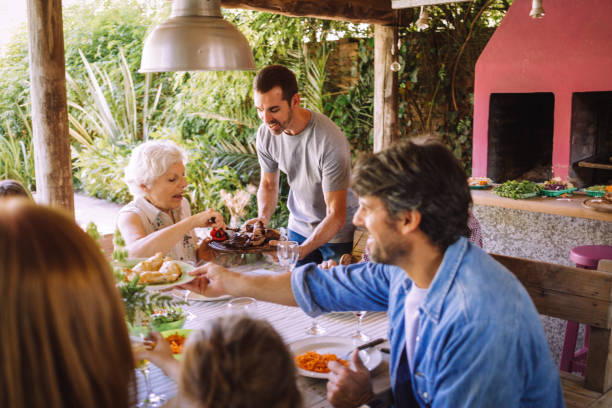 jeune adulte servant le barbecue à sa famille - argentinian ethnicity photos et images de collection