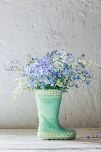 istock spring flowers in vase on background white old wall 1201352347