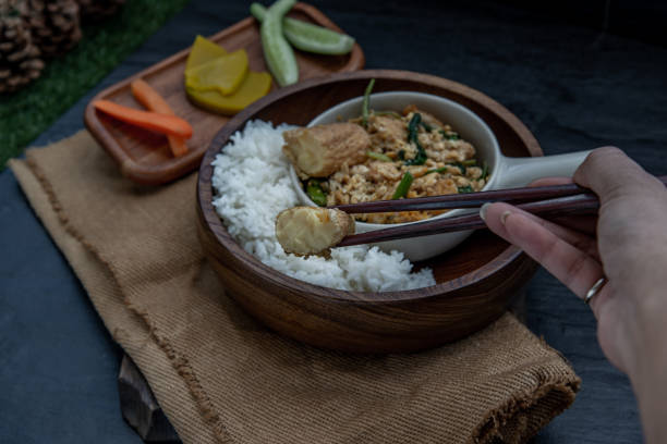 istock The hand is using chopsticks to pick up  Stir fried egg tofu with spring onion with Herbs vegetables served with steamed rice in wooden bowl. 1201355397