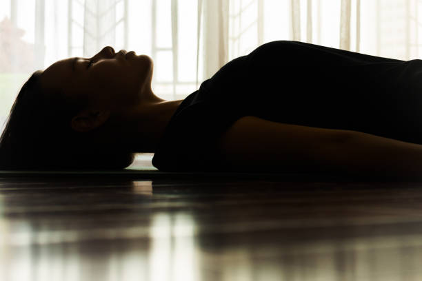 une femme s'étendant sur le tapis de yoga détendant. méditation. - mental health depression silhouette hysteria photos et images de collection