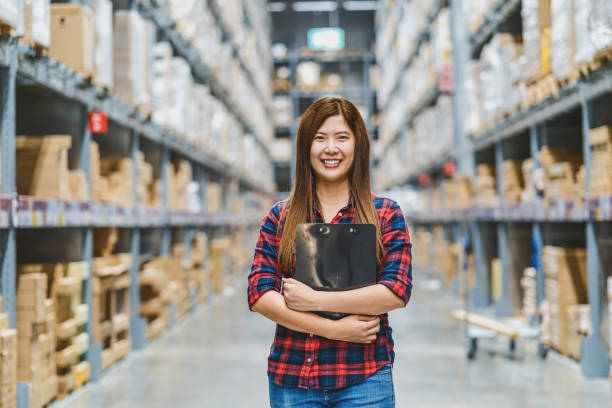 アジアの女性倉庫労働者の肖像画は、倉庫内の商品在庫をチェックするためのクリップボードを保持しています - warehouse manager place of work portrait ストックフォトと画像
