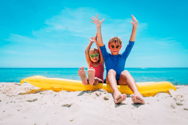 istock happy cute boy and girl with floatie on beach vacation 1201373728