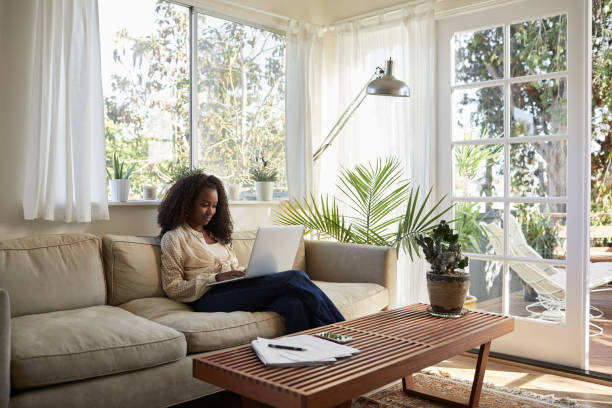 istock Smiling woman sitting on her sofa using a laptop 1201383154