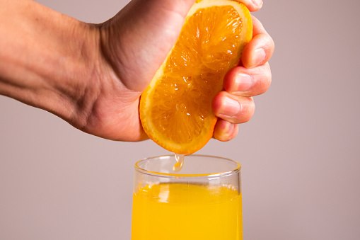 orange juice pouring into glass from jug on table with dark background