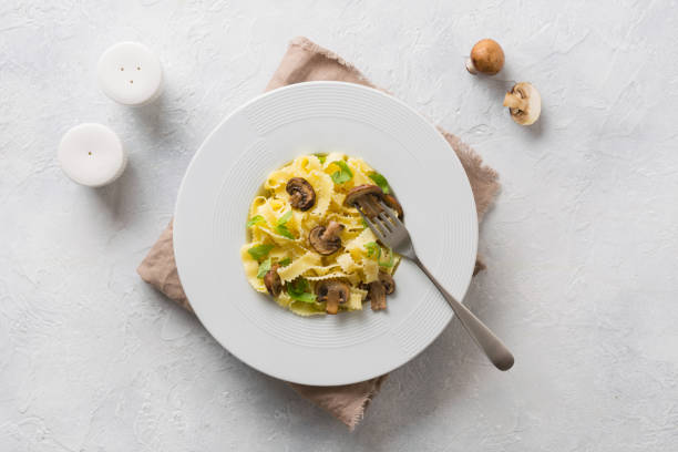 Spaghetti reginelle pasta with mushrooms on white. Tasty healthy dinner. View from above.