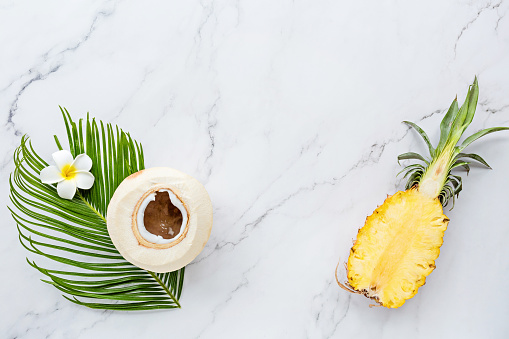 Summer composition. Tropical palm leaf, coconut, pineapple on white marble background. Summer concept. Flatlay, top view, mockup, banner, copy space