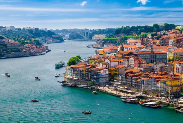 Photo of Portugal, Porto in June, Douro river, panoramic view of old town, tourist centre of Porto, unusual magic sunny Porto, light white clouds over Porto, colorful houses with red roofs in Porto