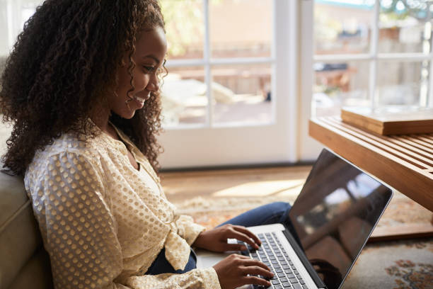 istock Young woman smiling while using a laptop at home 1201385887