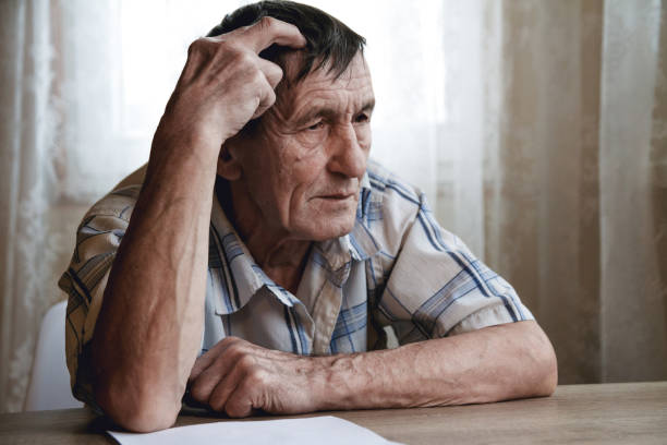 Senior sitting at the table and thinking about something or forg