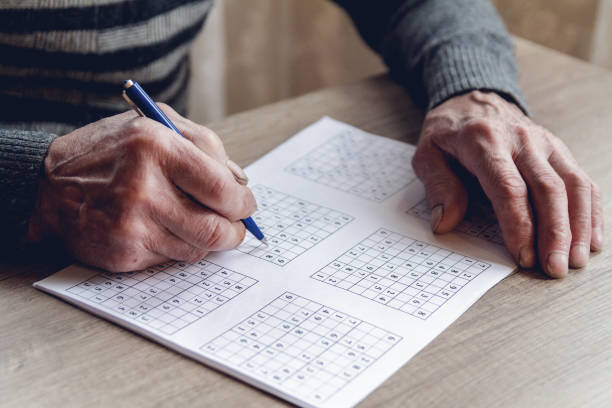 istock Senior solves sudoku or a crossword puzzle to slow the progressi 1201387175