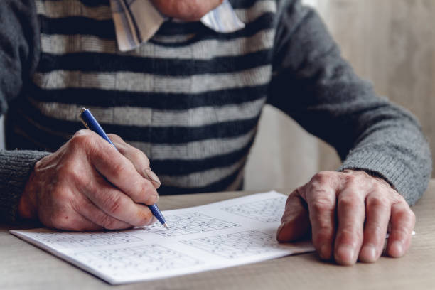 istock Senior solves sudoku or a crossword puzzle to slow the progressi 1201387247