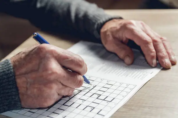 Elderly man solves sudoku or a crossword puzzle to slow the progression of Alzheimer's disease