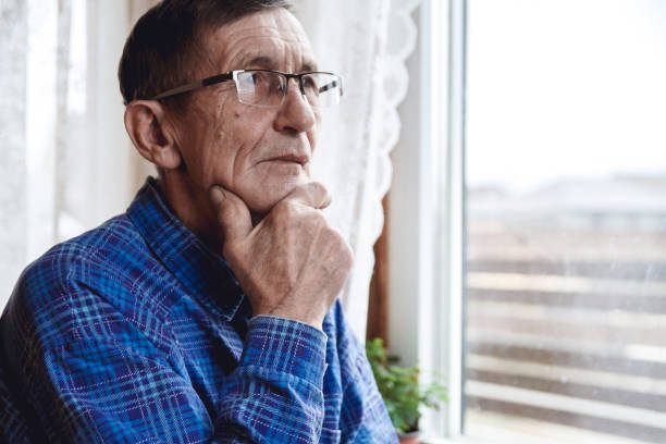 istock Senior standing at the window and thinking about something or fo 1201387326