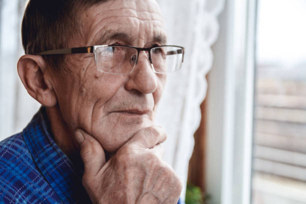istock Senior standing at the window and thinking about something or fo 1201387358