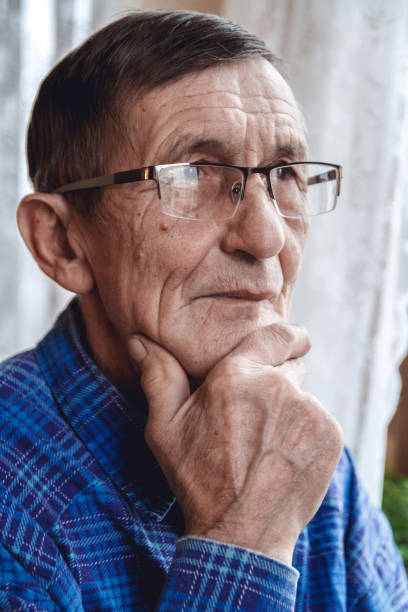 istock Senior standing at the window and thinking about something or fo 1201387376