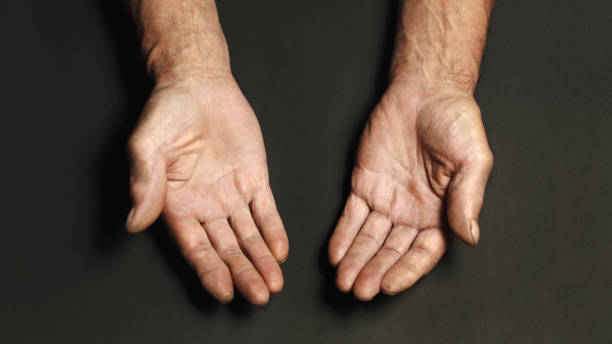 istock Wrinkled hands of an elderly man on a table close-up on a black 1201387924