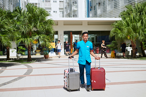 Boracay Island, Aklan, Philippines -January 13, 2019: Young male filipino hotel employee is helping guests with their luggage at the entrance area