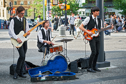 Vancouver, B.C., Canada - June 21, 2012: Three student Beatles revival musicians performing openly in downtown area to improve their budget