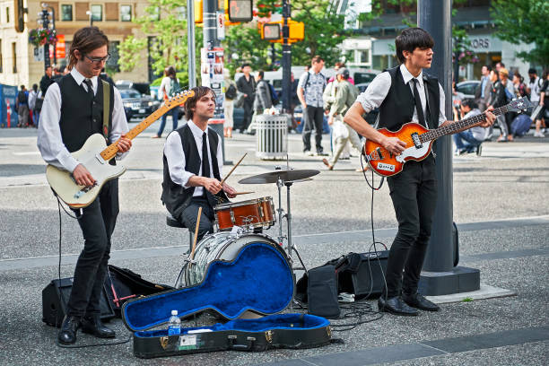 Three student Beatles revival musicians playing Vancouver, B.C., Canada - June 21, 2012: Three student Beatles revival musicians performing openly in downtown area to improve their budget beatles stock pictures, royalty-free photos & images